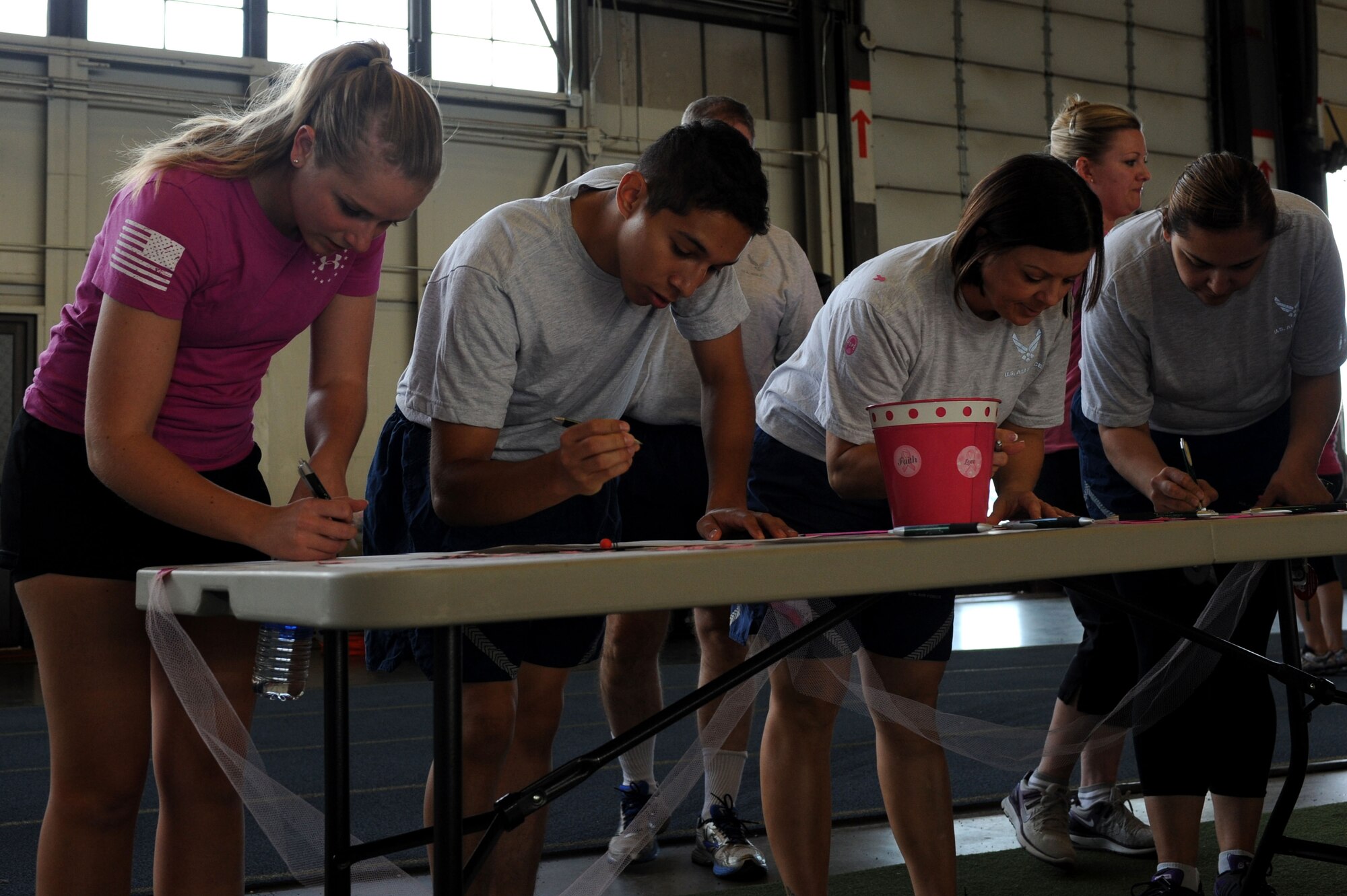 Ellsworth Airmen sign in at the registration table for the Breast Cancer Awareness Month walk-a-thon at the Pride Hangar at Ellsworth Air Force Base, S.D., Oct. 15, 2014. More than 140 people participated in the annual event, which was intended to help raise awareness for breast cancer, the dangers of the disease and what steps people can take to catch it early. (U.S. Air Force photo by Senior Airman Hailey R. Staker/Released)  
