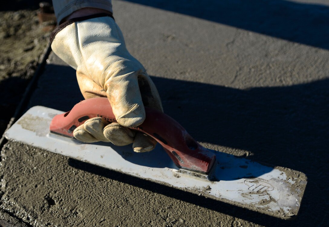 A U.S. Air Force Airman assigned to the 633rd Civil Engineer Squadron flattens concrete for the new F-15 Eagle static display at Langley Air Force Base, Va., Oct. 17, 2014. The 1st Fighter Wing Association funded the project, which gave Langley Airmen a chance to train on skills they need in deployed locations. (U.S. Air Force photo by Senior Airman Austin Harvill/Released) 