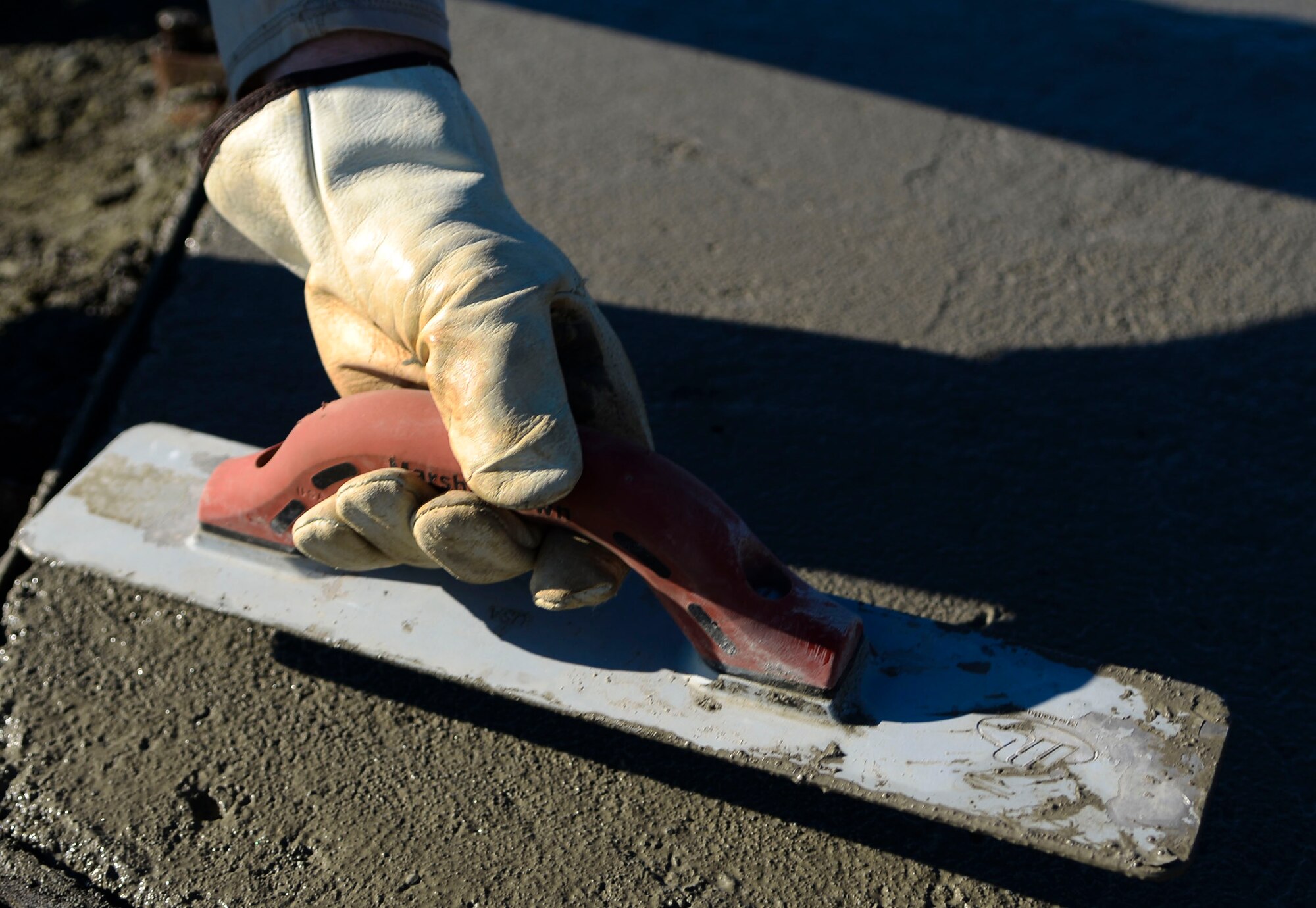 A U.S. Air Force Airman assigned to the 633rd Civil Engineer Squadron flattens concrete for the new F-15 Eagle static display at Langley Air Force Base, Va., Oct. 17, 2014. The 1st Fighter Wing Association funded the project, which gave Langley Airmen a chance to train on skills they need in deployed locations. (U.S. Air Force photo by Senior Airman Austin Harvill/Released) 