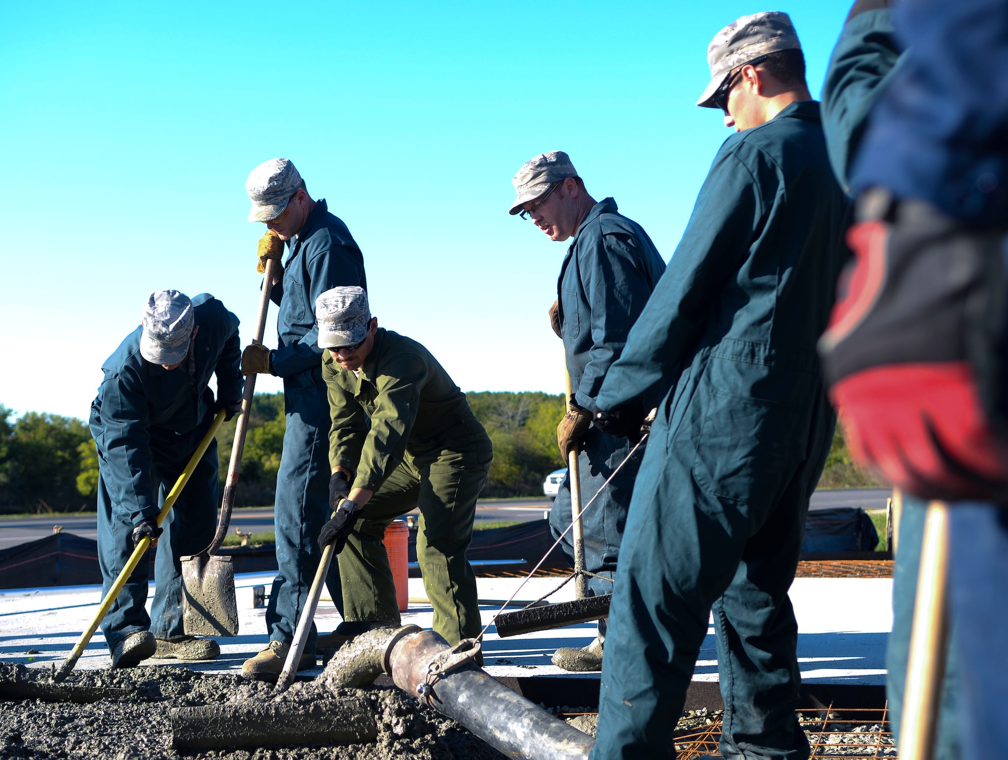 U.S. Air Force Airmen from the 633rd Civil Engineer Squadron pour concrete for the new F-15 Eagle static display at Langley Air Force Base, Va., Oct. 17, 2014. The 633rd CES personnel are using this opportunity to enact a troop training project, where Airmen from multiple career fields within the 633rd CES perform the job instead of contractors. (U.S. Air Force photo by Senior Airman Austin Harvill/Released) 