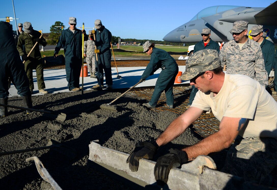 U.S. Air Force Airmen from the 633rd Civil Engineer Squadron pour concrete for the new F-15 Eagle static display at Langley Air Force Base, Va., Oct. 17, 2014. Aside from beautifying the grounds around the display, the concrete is vital to the structural integrity of the display. (U.S. Air Force photo by Senior Airman Austin Harvill/Released)