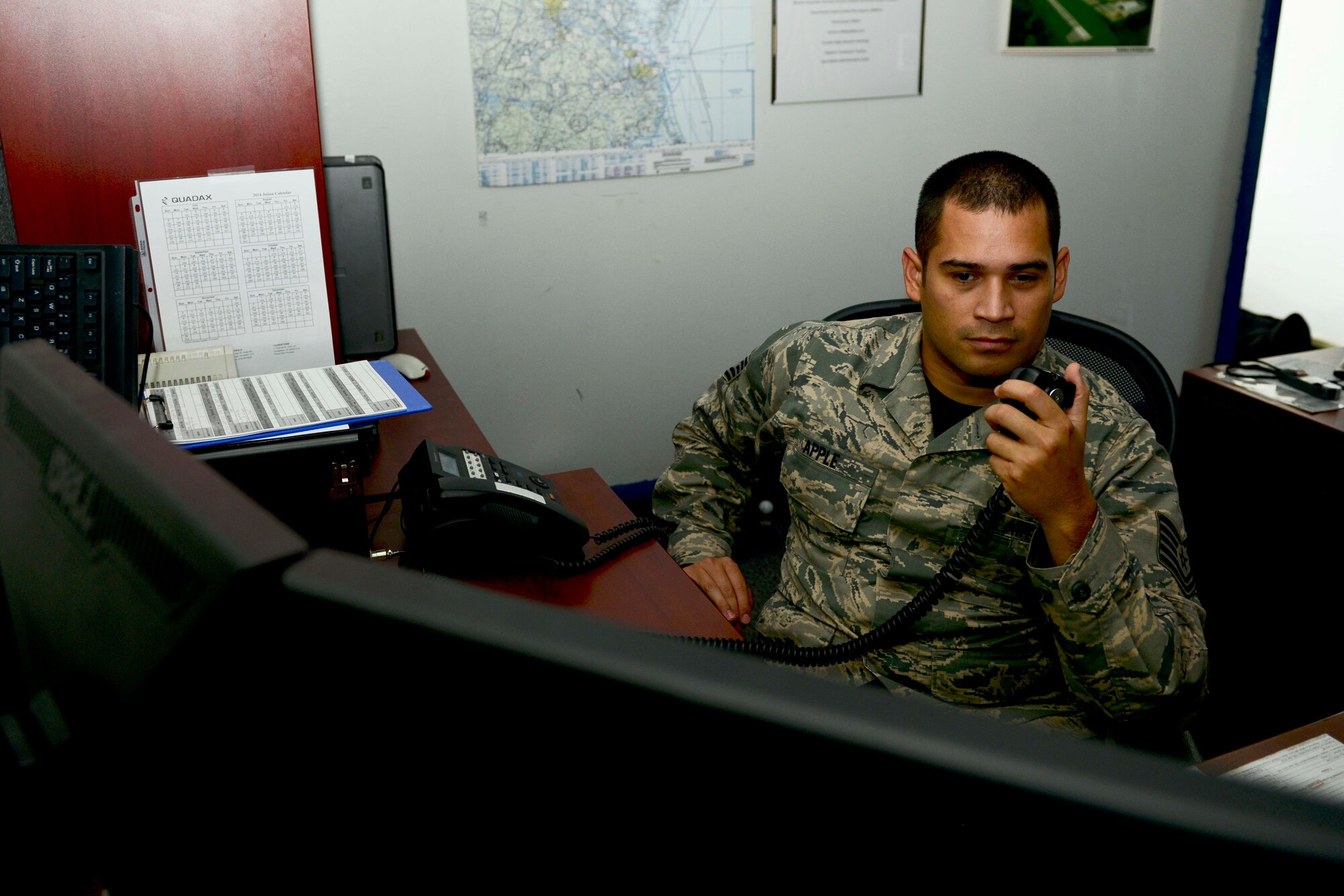 U.S. Air Force Tech. Sgt. John Apple, 1st Operations Support Squadron weather flight assistant section chief, radios in the current weather status at Fort Eustis, Va., Oct. 17, 2014. The weather flight gathers severe weather possibilities, compiles it and sends it to the Emergency Operations Center on post, who then distributes it out to the units.
 (U.S. Air Force photo by Airman 1st Class Kimberly Nagle/Released) 
