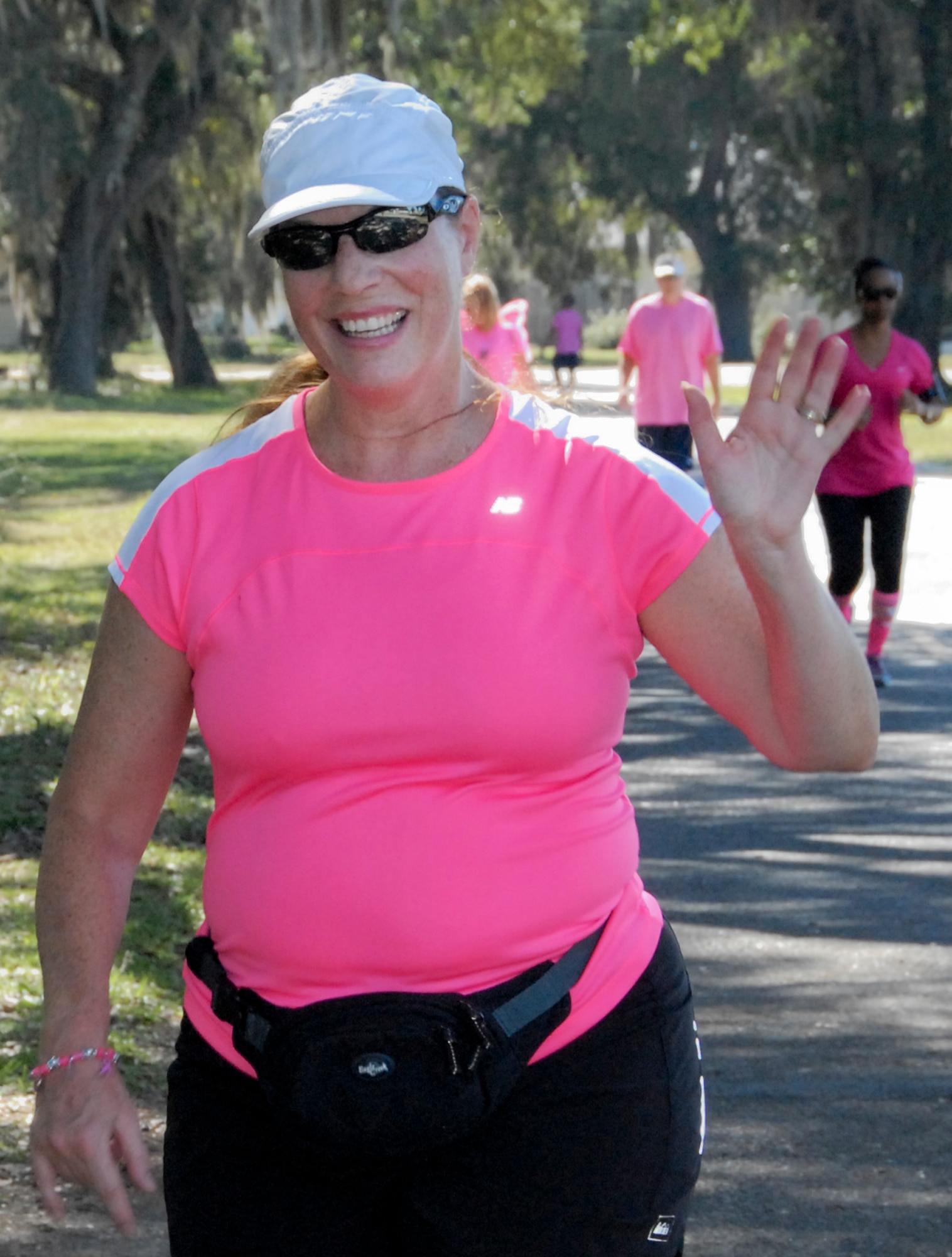 A runner gives a cheerful wave during the 7th Annual Breast Cancer Awareness 5k run Oct. 17 at Eglin Air Force Base, Fla.  Civilian Health Promotion Services was also on hand providing information on breast cancer risk factors, symptoms and screenings.  The event was held to promote breast cancer awareness and the importance of self-examination to catch the disease in its early stages.  (U.S. Air Force photo/Kevin Gaddie)