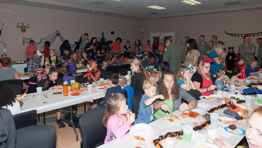 Spouses and children enjoy activities and a meal Oct. 16, 2014, at the Youth Center on Dover Air Force Base, Del. Along with the dinner, a haunted house was built outside, featuring smoke machines, strobe lights and dressed up volunteers to scare people as they walked through. (U.S. Air Force photo/Airman 1st Class Zachary Cacicia)