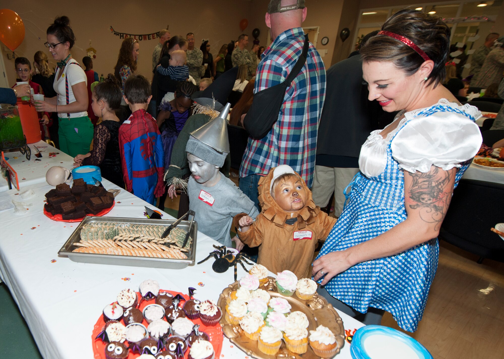 Amie Ferguson, wife of Tech. Sgt. Caleb Ferguson, 436th Security Forces Squadron, and their sons, Shaun and Colton, stand at the dessert table Oct. 16, 2014, at the Youth Center on Dover Air Force Base, Del. The Fergusons dressed up as Dorothy, the Cowardly Lion and the Tin Man from “The Wizard of Oz.” (U.S. Air Force photo/Airman 1st Class Zachary Cacicia)