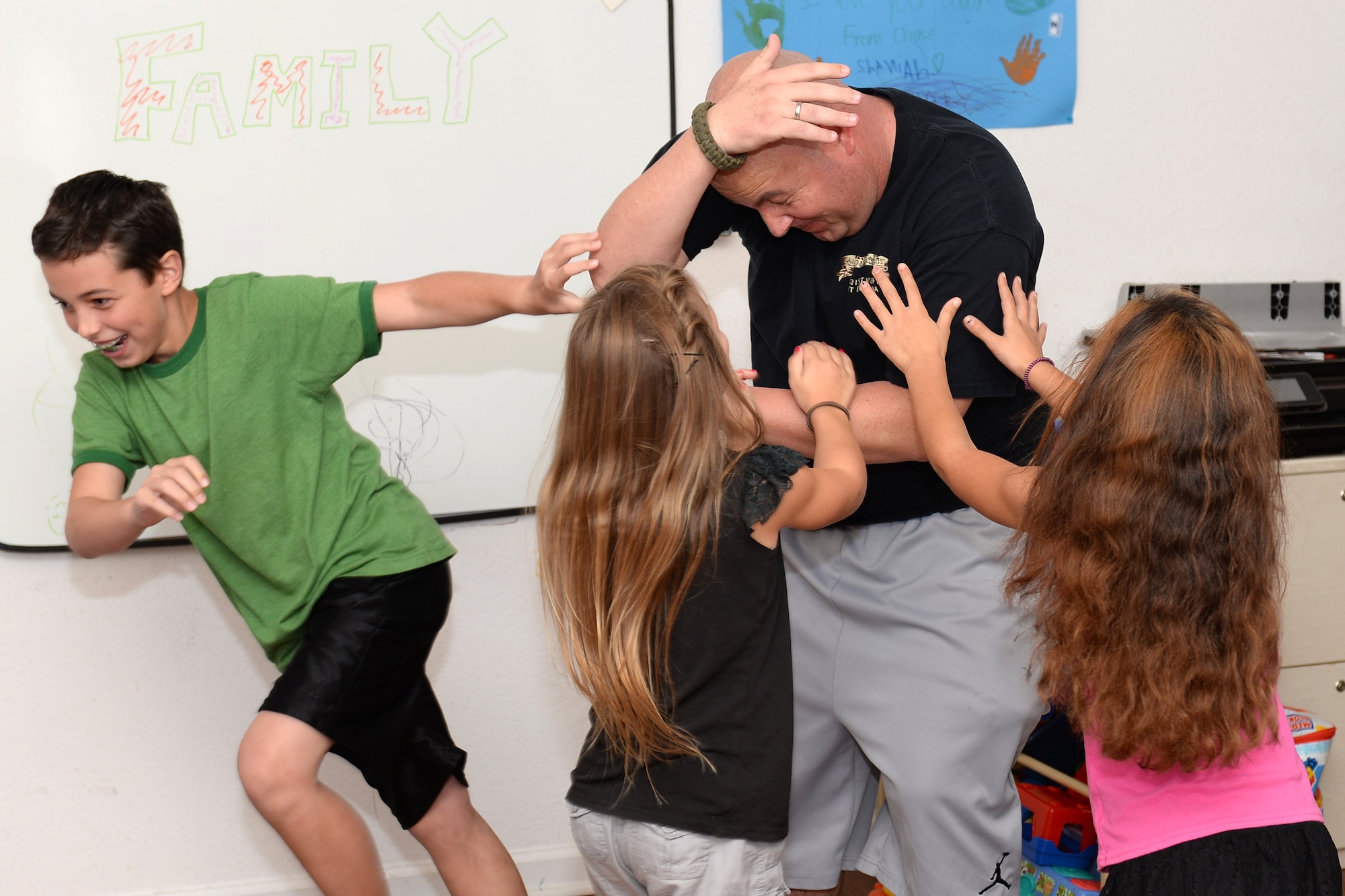 U.S. Army Spc. Robert Philman, 221st MP Det. patrolman, wrestles with his children and Sgt. Avery Arrington’s daughter in the Arrington’s home at Fort Eustis, Va., Oct. 15, 2014. Although Philman doesn’t have use of his right hand, he still manages to play with his family when they spend time with him at the Arrington’s home. (U.S. Air Force photo by Staff Sgt. Teresa J. Cleveland/Released)