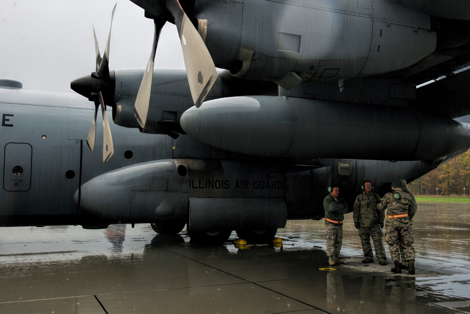 U.S. Air Force Airmen from the 182nd Airlift Wing, Illinois Air National Guard, Peoria, Ill., keep dry under the wing of their C-130 Hercules cargo aircraft during a training mission at Powidz Air Base, Poland, Oct. 20, 2014. The ANG continually sends Airmen and aircraft to Europe to help provide a determined presence during uncertain times. Air Guardsmen work alongside numerous NATO partners, ensuring America's commitment to regional security and stability. (U.S. Air Force photo by Staff Sgt. Christopher Ruano/Released)