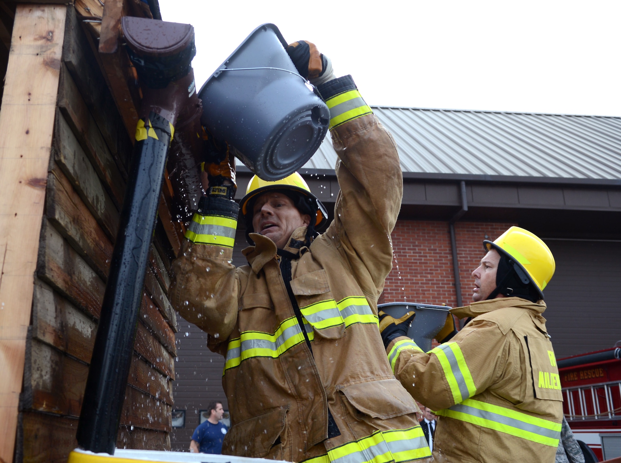 U.S. Air Force Chief Master Sgt. Tracy Jones, left, 100th Air Refueling Wing command chief, pours water onto the roof of a shed Oct. 17, 2014, during the Fire Prevention Week “Chiefs versus Eagles” fire muster on RAF Mildenhall, England. The Chiefs won with a time of 7:16. (U.S. Air Force photo/Airman 1st Class Dillon Johnston/Released)