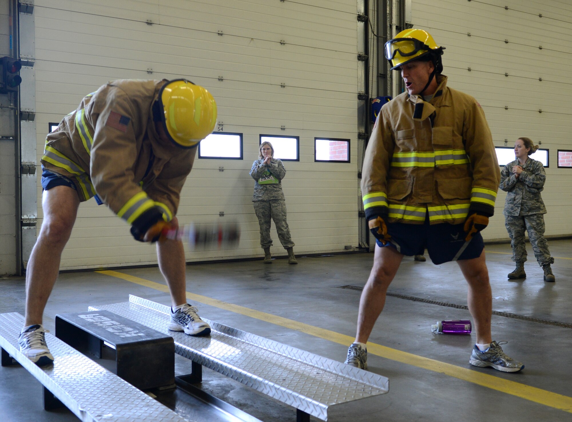 U.S. Air Force Chief Master Sgt. Tracy Jones, left, 100th Air Refueling Wing command chief, uses a sledge hammer to move a sled Oct. 17, 2014, during the Fire Prevention Week “Chiefs versus Eagles” fire muster on RAF Mildenhall, England. The muster required teams to perform a series of firefighter-related physical activities in the shortest amount of time possible. (U.S. Air Force photo/Airman 1st Class Dillon Johnston/Released)