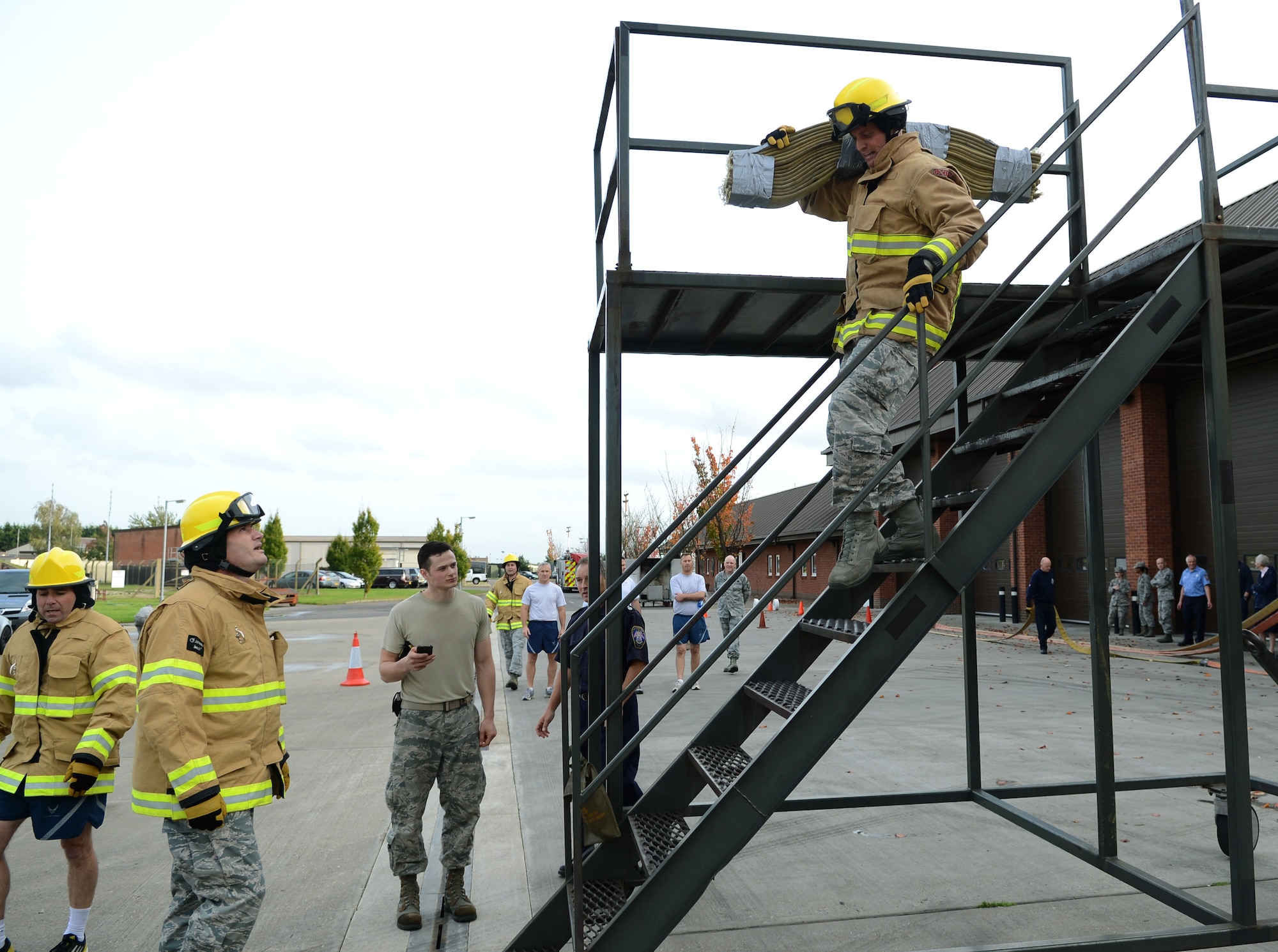 U.S. Air Force Col. David Cox, right, 100th Air Refueling Wing vice commander, runs down a flight of stairs while carrying a hose Oct. 17, 2014, during the Fire Prevention Week “Chiefs versus Eagles” fire muster on RAF Mildenhall, England. The Chiefs won with a time of 7:16. (U.S. Air Force photo/Airman 1st Class Dillon Johnston/Released)