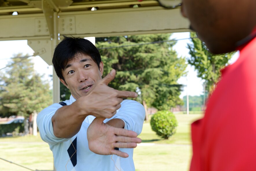 Tomoaki Kibamoto, Par 3 Golf Course instructor, explains swing techniques to a base resident during the Free Golf Clinic at Yokota Air Base, Japan, Oct. 18, 2014. Kibamoto has been golfing for 20 years and uses his knowledge to help Yokota golfers improve their game. (U.S. Air Force photo by Staff Sgt. Cody H. Ramirez/Released) 