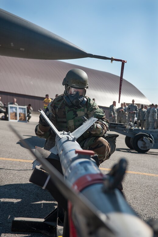 Senior Airman Guy Self, 51st Aircraft Maintenance Squadron 36th Aircraft Maintenance Unit weapons load crew member, assists Staff Sgt. Joshua Groom, 51st AMXS 36th AMU weapons load crew team chief, with his gas mask during a quarterly load crew competition at Osan Air Base, Republic of Korea, Oct. 17, 2014. Using the buddy system while putting on chemical warfare gear helps to ensure everything is put on properly. (U.S. Air Force photo by Senior Airman Matthew Lancaster)