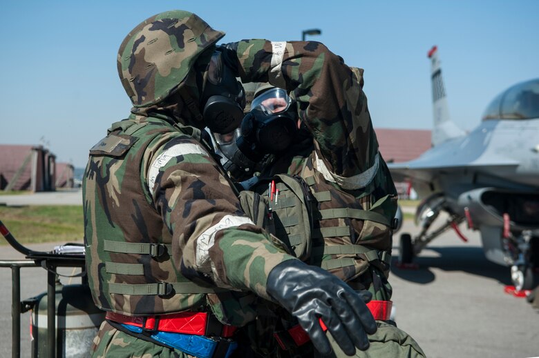 Senior Airman Guy Self, 51st Aircraft Maintenance Squadron 36th Aircraft Maintenance Unit weapons load crew member, assists Staff Sgt. Joshua Groom, 51st AMXS 36th AMU weapons load crew team chief, with his gas mask during a quarterly load crew competition at Osan Air Base, Republic of Korea, Oct. 17, 2014. Using the buddy system while putting on chemical warfare gear helps to ensure everything is put on properly. (U.S. Air Force photo by Senior Airman Matthew Lancaster)