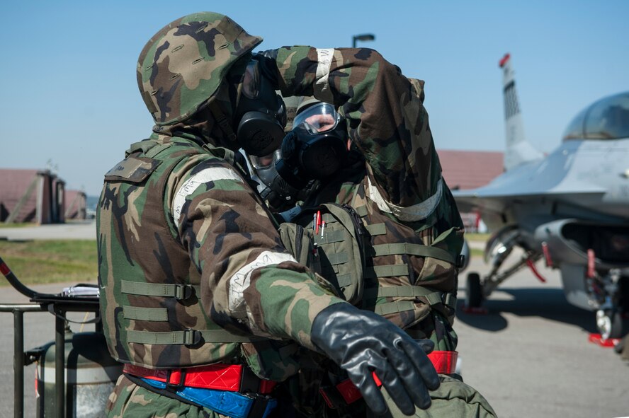 Senior Airman Guy Self, 51st Aircraft Maintenance Squadron 36th Aircraft Maintenance Unit weapons load crew member, assists Staff Sgt. Joshua Groom, 51st AMXS 36th AMU weapons load crew team chief, with his gas mask during a quarterly load crew competition at Osan Air Base, Republic of Korea, Oct. 17, 2014. Using the buddy system while putting on chemical warfare gear helps to ensure everything is put on properly. (U.S. Air Force photo by Senior Airman Matthew Lancaster)