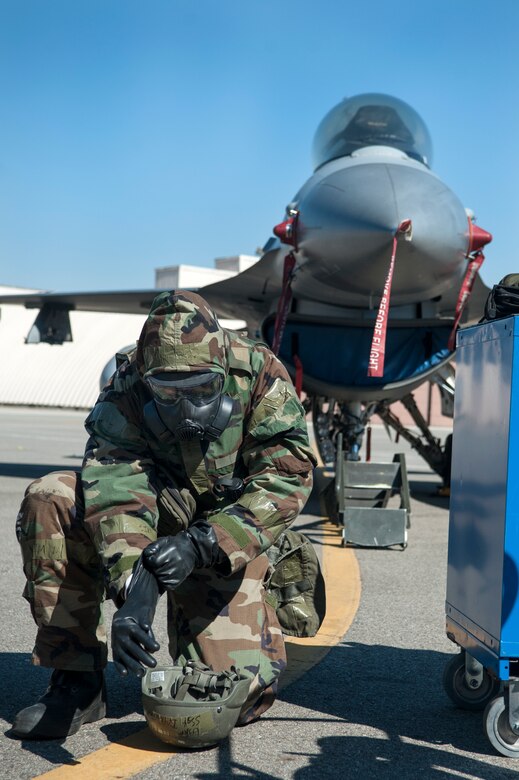 Staff Sgt. Jerry Dye, 8th Aircraft Maintenance Squadron 80th Aircraft Maintenance Unit weapons load crew team chief, Kunsan Air Base, Republic of Korea, puts on chemical warfare gear during a quarterly load crew competition at Osan Air Base, ROK, Oct. 17, 2014. Chemical warfare gear is worn during this competition to show the capability of loading while in chemical warfare gear. (U.S. Air Force photo by Senior Airman Matthew Lancaster)