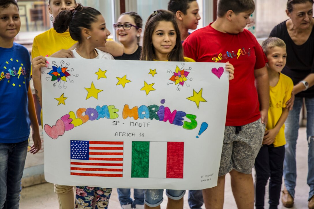 Students hold a sign welcoming the Marines and Sailors of Special-Purpose Marine Air-Ground Task Force Africa 14 to their school. Service members with SP-MAGTF Africa read to the students, donated books, told them about themselves and got to know the individual children, Sept. 25, 2014. (U.S. Marine Corps photo by Cpl. Shawn Valosin)