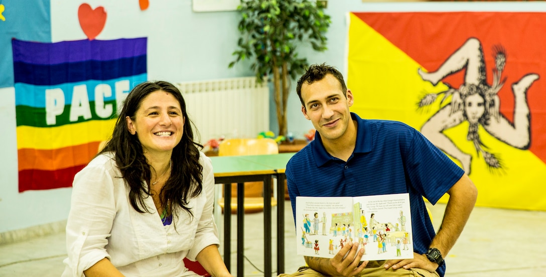 Petty Officer third class Michael Fallone (right), a corpsman with Special-Purpose Marine Air-Ground Task Force Africa 14, and a local school teacher (left), read to students during a community relations event at a local elementary school, the Istituto Comprensivo Cesare Battisti of Catania, in the San Cristoforo neighborhood, Sept. 25, 2014. During the event Fallone would read the book in English and the teacher translated to the students. She then had the students to repeat the English words, encouraging the students in their English studies. (U.S. Marine Corps photo by Cpl. Shawn Valosin)