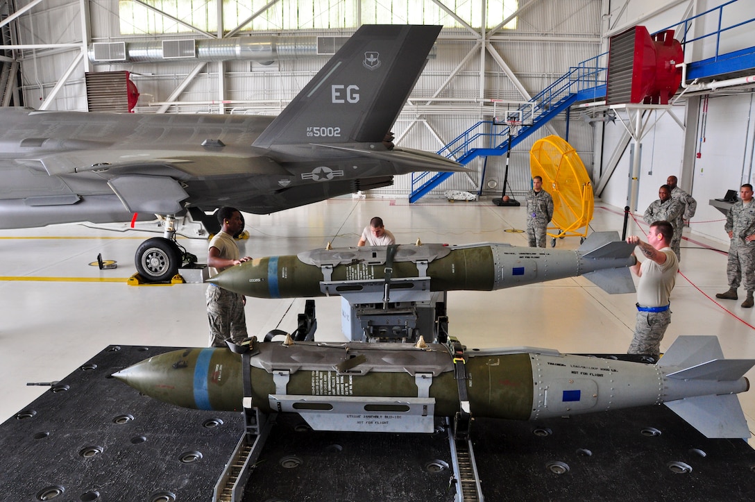 Airmen with the 58th Aircraft Maintenance Unit crew one prepare to load a GBU-31 joint direct attack munition on to an F-35A Lightning II during a qualification load Oct. 10, 2014, at Eglin Air Force Base, Fla. The F-35A is now one step closer to its initial operational capability with the first weapons load crew qualification. The newly qualified crewmembers will continue to hone their skills and become experts at their jobs so they can train the weapons load crews at other bases receiving the F-35A. (U.S. Air Force photo/Staff Sgt. Marleah Robertson)