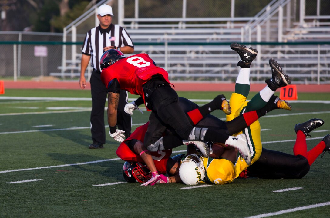 A cast of Marine Corps Air Station Miramar Falcons tackle the 3rd Amphibian Assault Battalion Gators running back during a football game at Paige Fieldhouse aboard Marine Corps Base Camp Pendleton, Calif., Oct. 21. The Falcons defeated the Gators 30-0 in their first playoff game.