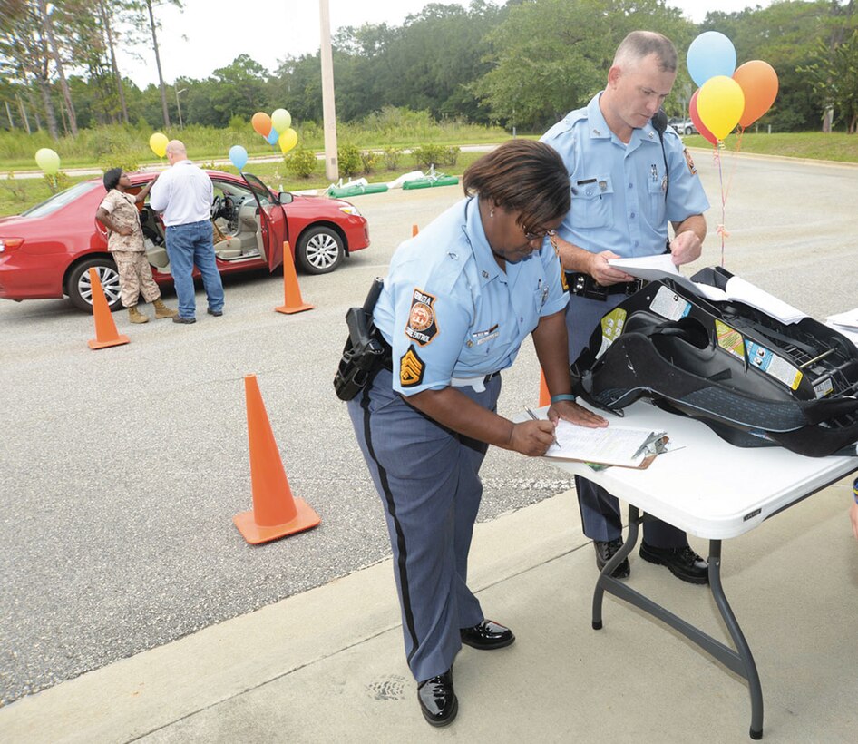 Shawn Urquhart (left), post commander, and Robert Corbin, trooper, Georgia State Patrol, Post 40, Albany, Georgia, inspect a child's car seat during a car-seat safety check held at the Child Development Center, Marine Corps Logistics Base Albany, recently. 
