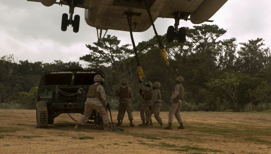 Marines grab a hook hanging from a CH-53E Super Stallion helicopter to attach to a Humvee Oct. 7 here. The training, known as external-lift training, was completed by the pilot and crew of the CH-53E, and the landing support specialists. To conduct the training, the aircraft was brought to a hover above the Humvee, allowing the Marines below to attach hooks to the harness around the vehicle. The Marines are landing support specialists with Combat Logistics Battalion 4, Combat Logistics Regiment 3, 3rd Marine Logistics Group, III Marine Expeditionary Force. The aircraft is with Marine Heavy Helicopter Squadron 361, currently assigned to Marine Aircraft Group 36, 1st Marine Aircraft Wing, III MEF, under the unit deployment program.