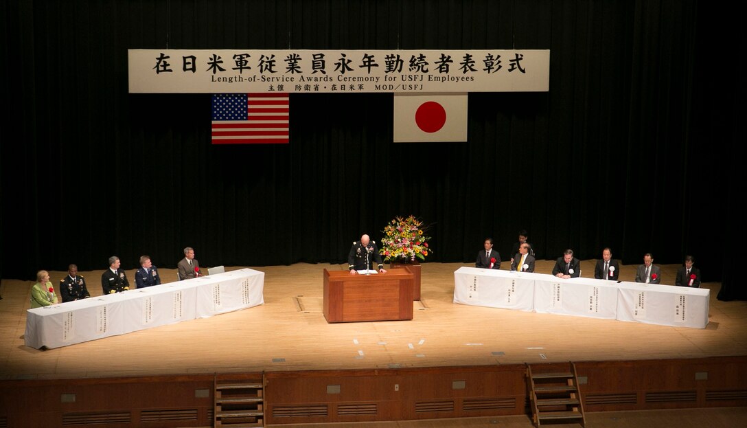 Army Col. David W. Detata expresses his gratitude toward master labor contract and indirect hire agreement employees at the 2014 Length of Service Awards Ceremony for U.S. Forces Japan employees Oct. 15 at the Okinawa Convention Center in Ginowan, Okinawa. He, along with representatives from the other branches of service, helped recognize 855 MLCs and IHA hires who have reached 10, 20, 30 and 40 years of service for USFJ. Out of the 855, 243 individuals were recognized for their service with the Marine Corps in Okinawa. USFJ employees are Japanese citizens hired by the Government of Japan to work for USFJ in various capacities, from interpreters to medical technicians. Detata is the chief of Okinawa Area Field Office, USFJ.