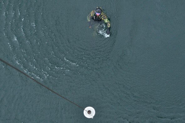 Capt. Matthew Arnold swims towards a hoist from a UH-1N Iroquois helicopter during a water operations training scenario Oct. 17, 2014, at Long Lake, Washington. As part of the water operations training, Arnold entered the water, waited for the pilot to make several passes to familiarize themselves on approach and hoisting procedures over water. Once in the water and actions were complete, swimmers would communicate to the pilots that they were ready for pick-up using hand signals over their heads.  The flight engineer would then hoist the swimmers up from approximately 40 feet.  Some pilots were tasked to complete several attempts of ‘helo-casting’ and hoisting to complete their search and rescue certification while others were trainers or used the mission as re-certification. (U.S. Air Force photo/Staff Sgt. Alexandre Montes)