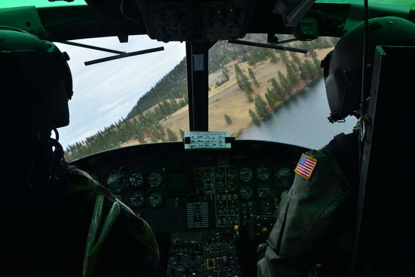 Maj. Dee Bochte and Capt. Josiah Hart, 36th Rescue Flight helicopter pilots, look for safe landing zone for freefall swimmers from the 336th Training Group during a water operations training scenario Oct. 17, 2014, at Long Lake, Washington. The training was held to train new helicopter pilots and aircrew assigned to the 36th Rescue Flight with maneuvering and retracting persons from water situations. On average, the unit responds from 15 to 20 emergencies each year and is credited with saving more than 687 lives since its inception in 1971. These missions included search and rescue for crashed aircraft and lost hikers, fisherman and hunters; notification and evacuation of backcountry personnel in the face of Washington's worst fire season in seven years; transport of a critically-injured gunshot victim; and the rescue of a seriously injured back-country snowboarder with a 200-foot hoist using night vision in Sandpoint, Idaho. (U.S. Air Force photo/Staff Sgt. Alexandre Montes)