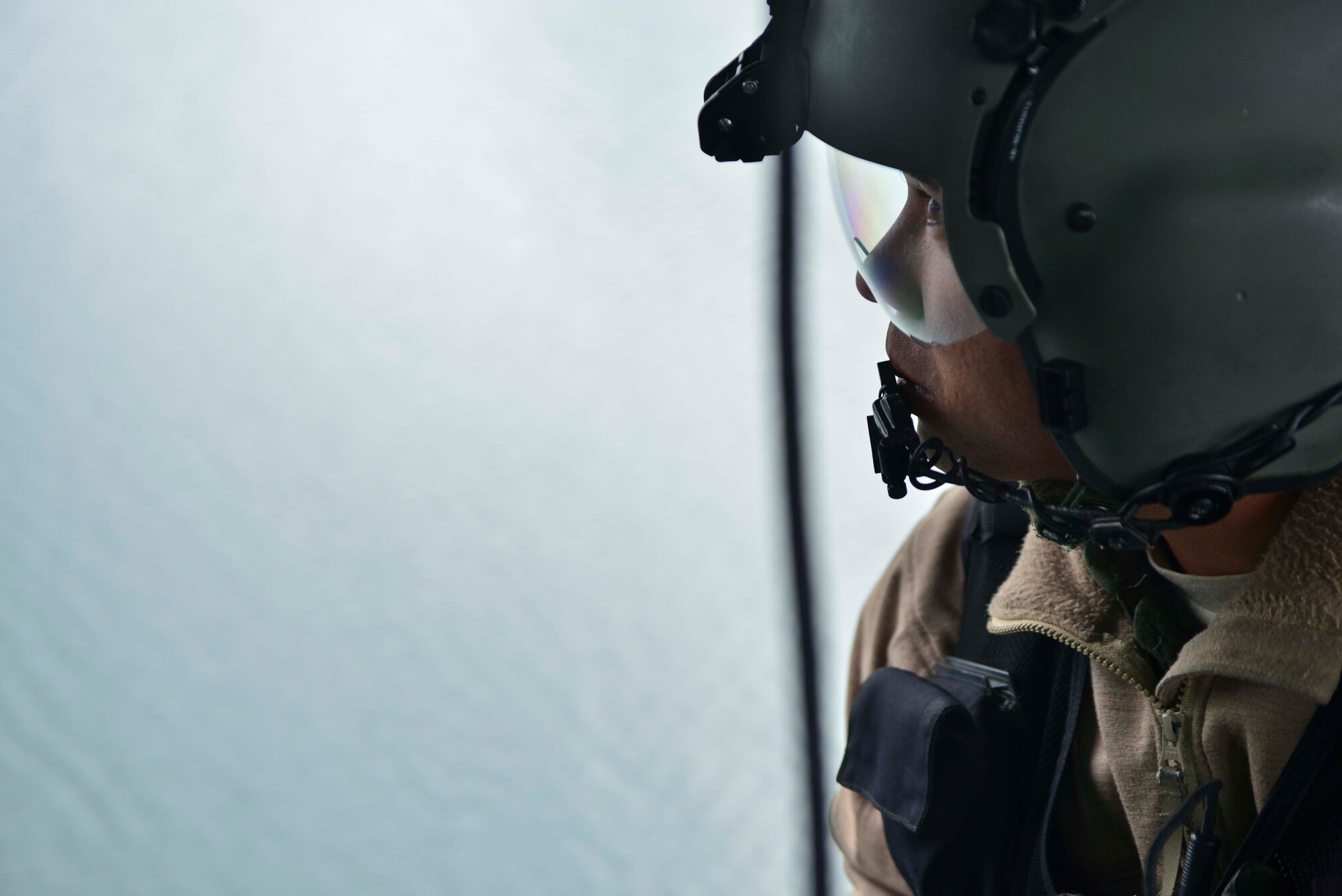 Staff Sgt. Jeremy Bernite, 36th Rescue Flight aircrew flight engineer, looks out the bay door of a UH-1N Iroquois helicopter during water operations training scenario for combat rescue officers from the 336th Training Group and 36th RQF pilots Oct. 17, 2014, at Long Lake, Washington. Aircrew engineers go through 25 days of rigorous training consisting undergraduate course, combat survival training, water survival, non-parachuting survival and a basic flight engineer course. Engineers maintain fixed-wing or rotary wing helicopters aircraft systems. They will monitor hydraulics, engine power during climb and approach while communicating with the pilots to ensure exact placement of the aircraft for extraction and hoist control. (U.S. Air Force photo/Staff Sgt. Alexandre Montes)