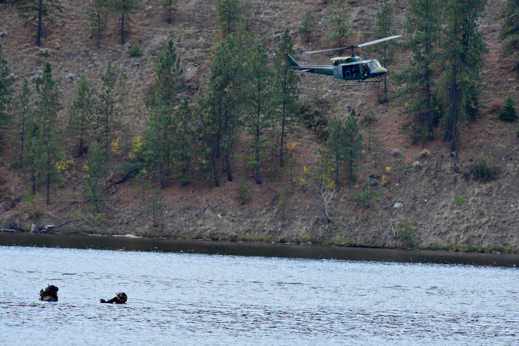 Capt. Matthew Arnold, 66th Training Squadron, alongside Capt. Marcus Truman, 336th Training Group combat rescue officers, wade in a lake while they wait for pilots and aircrew from the 36th Rescue Flight to hoist them onto the helicopter during a water operations refresher course for combat rescue officers Oct. 17, 2014, at Long Lake, Washington. Water survival training introduces members of the military to several water survival scenarios. It also allows them to reinforce their water skills and practice them until they are comfortable in the water. During the training scenario, combat rescue officers practiced free-fall swimmer deployment, as it is the most efficient way to have a recovery crew to retract an isolated person in a time efficient manner. (U.S. Air Force photo/Staff Sgt. Alexandre Montes)