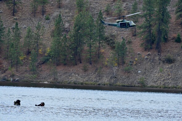Capt. Matthew Arnold, 66th Training Squadron, alongside Capt. Marcus Truman, 336th Training Group combat rescue officers, wade in a lake while they wait for pilots and aircrew from the 36th Rescue Flight to hoist them onto the helicopter during a water operations refresher course for combat rescue officers Oct. 17, 2014, at Long Lake, Washington. Water survival training introduces members of the military to several water survival scenarios. It also allows them to reinforce their water skills and practice them until they are comfortable in the water. During the training scenario, combat rescue officers practiced free-fall swimmer deployment, as it is the most efficient way to have a recovery crew to retract an isolated person in a time efficient manner. (U.S. Air Force photo/Staff Sgt. Alexandre Montes)