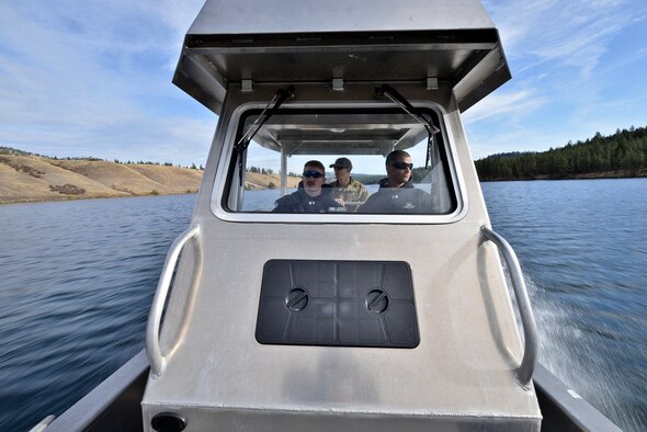 Airman 1st Class Gene Sauder, 336th Training Support Squadron aircrew flight equipment, Staff Sgt. Gary Roland, 66th Training Squadron water survival instructor and Senior Airman Justin Mason, 336th TRSS AFE, drive a boat along the lake looking for a safe landing zone for combat rescue officers during water operations training Oct. 17, 2014, at Long Lake, Washington. Water operations training helps combat rescue officers simulate response to isolated personnel in several water situations.  The watercraft crew comprised support personnel such as independent duty medical technicians, a safety diver and AFE airmen in case of an emergency.  (U.S. Air Force photo/Staff Sgt. Alexandre Montes) 