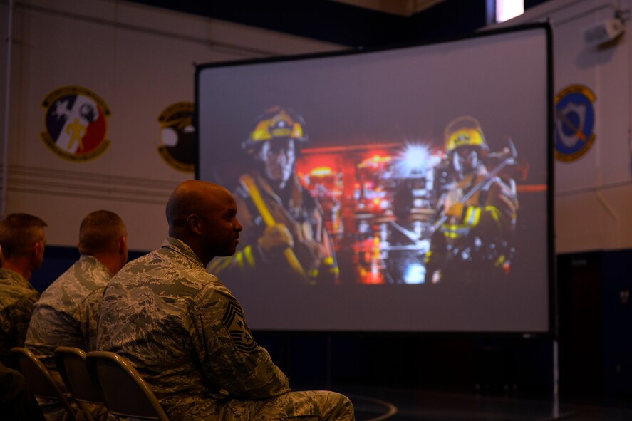 Chief Master Sgt. Lavon Coles, 50th Space Wing command chief, watches a photo slideshow of Team Schriever members, during a commander’s call at the fitness center Oct. 17, 2014, at Schriever Air Force Base, Colo. The call served as a time for 50th Space Wing members to gather and ask questions about the upcoming unit evaluation inspection here. (Air Force Photo/Christopher DeWitt)