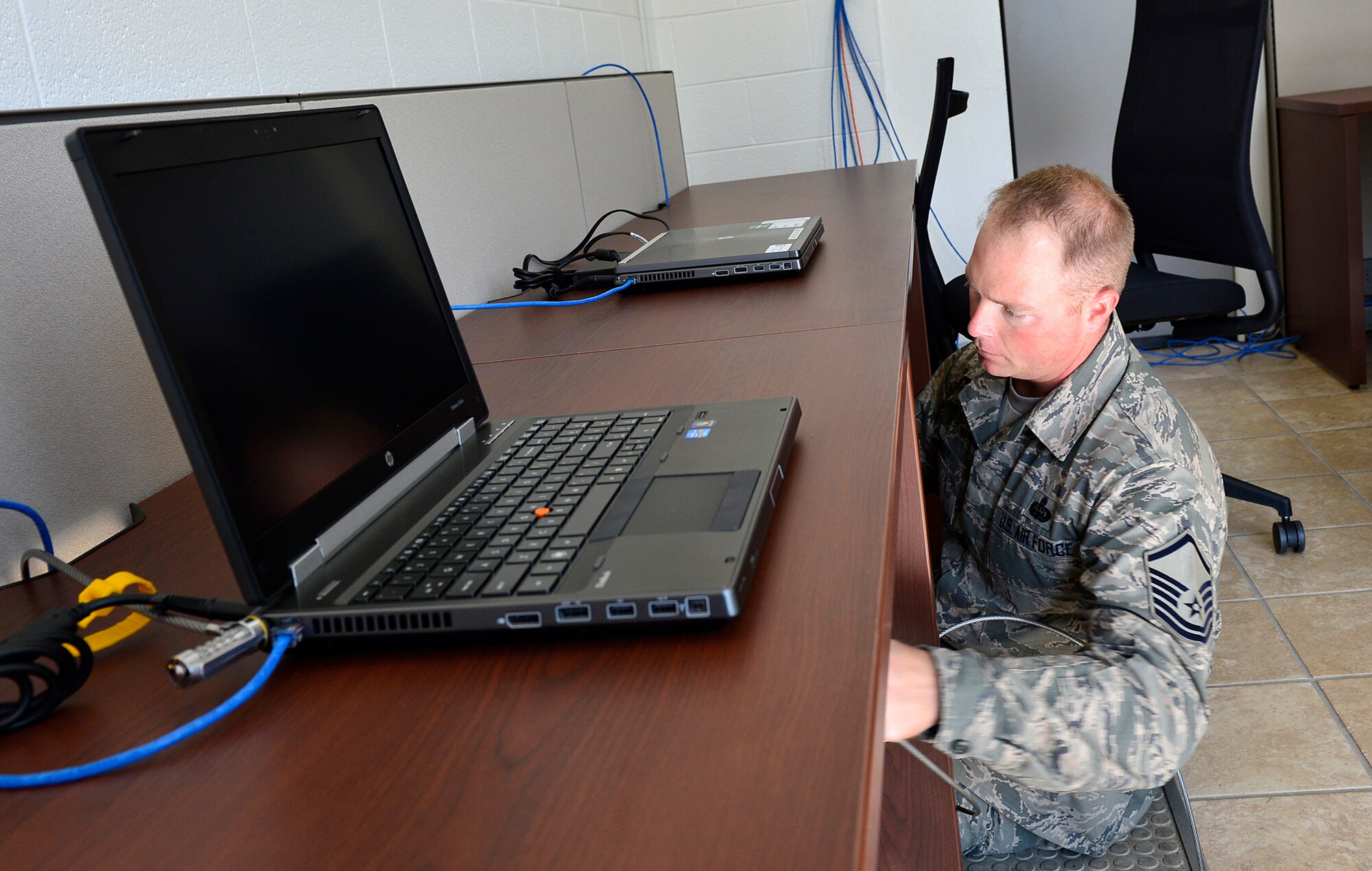 MCGHEE TYSON AIR NATIONAL GUARD BASE, Tenn. -- Master Sgt. Charles Hoover, Cyber Operations manager for the I.G. Brown Training and Education Center, installs cable locks Oct. 22, 2014, here on laptop computers in the Morrisey Hall classroom building. The 21 computers as well as recently installed office furniture are part of two cyber cafes coming online near the downstairs entrances. (U.S. Air National Guard photo by Master Sgt. Mike R. Smith/Released) 