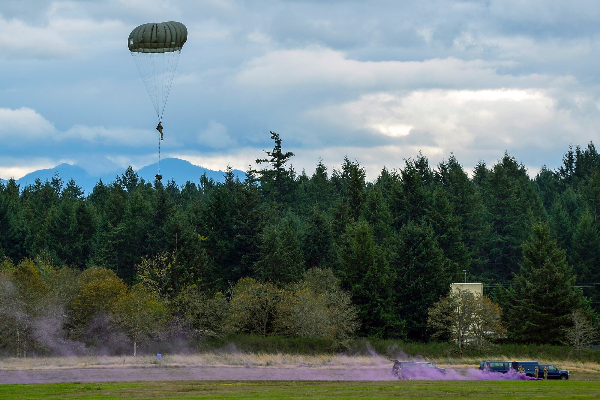 22nd Special Tactics Squadron combat controllers on the ground pop purple smoke marking the landing zone for their fellow Airmen jumping from a C-17 Globemaster III October 21, 2014, during a training exercise at Joint Base Lewis-McChord, Wash. The Special Tactics Airmen conducted the jump training to maintain proficiency as they prepare for upcoming deployments. (U.S. Air Force photo/SSgt Russ Jackson) 