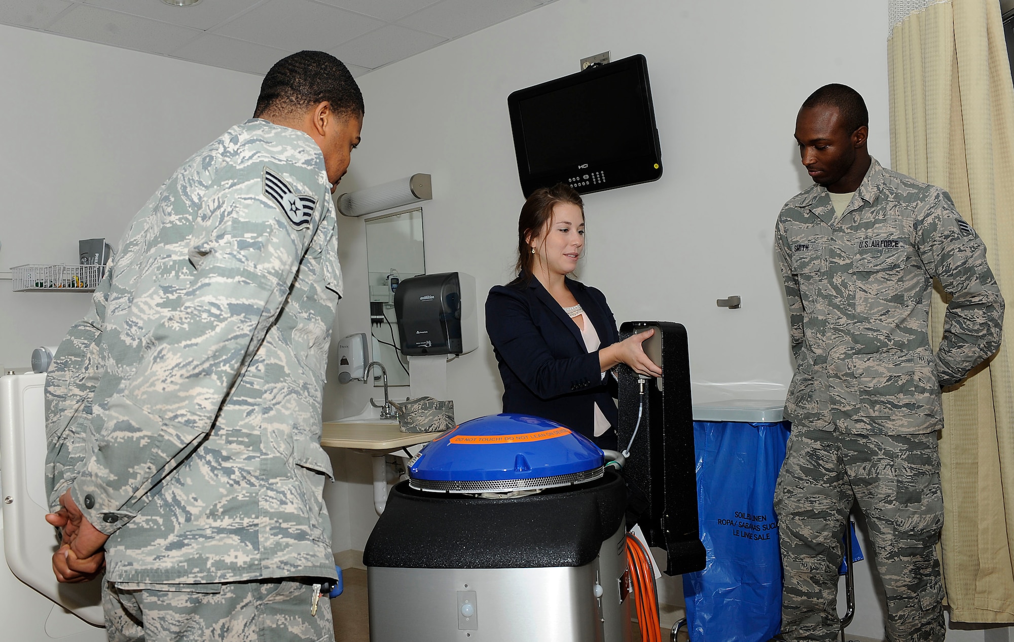 Geri Genant, Xenex Healthcare Services implementation manager, demonstrates the functions of “Saul,” a germ-zapping robot to U.S. Air Force Staff Sgt. Andru Jones and Senior Airman Ricky Smith 633rd Medical Support Squadron logistics personnel at Langley Air Force Base, Va., Oct. 20, 2014. Langley Air Force Base is the first Air Force installation to receive a robot that has the power to disinfect a room in five minutes and destroy Ebola on any surface in two minutes. (U.S. Air Force photo by Staff Sgt. Antoinette Gibson/Released)