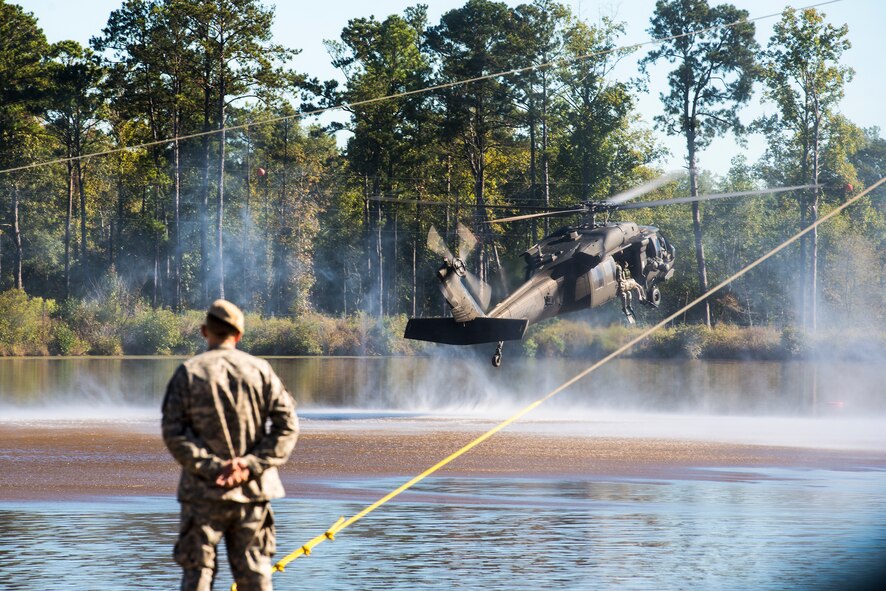 A U.S. Army Ranger School instructor watches as a UH-60 Black Hawk descends over a pond as part of a demonstration during a Ranger School graduation Oct. 17, 2014, at Fort Benning, Ga. During the demonstration, Rangers jumped from the Black Hawk into a pond, assaulted the coast and were then extracted by the helicopter. (U.S. Air Force photo by Airman 1st Class Ryan Callaghan/Released)