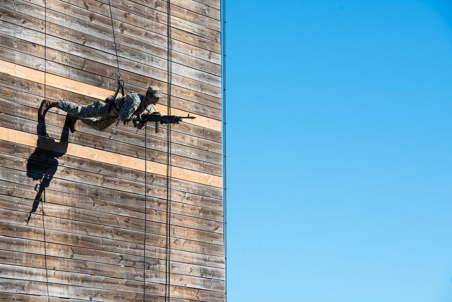 A U.S. Army Ranger carrying an M249 light machine gun rappels down a wall as part of a demonstration during a Ranger School graduation Oct. 17, 2014, at Fort Benning, Ga. Rangers are proficient in operations in urban, wooded, mountainous, jungle and swamp environments. (U.S. Air Force photo by Airman 1st Class Ryan Callaghan/Released)