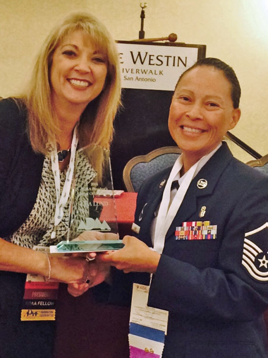 Lori A. Paschall, CDA, CPFDA, FADAA, American Dental Assistant Association (ADAA) president, Presents the ADAA President's Award to Master Sgt. Lisa Lund, METC Air Force Dental Assistant program course supervisor, during the ADAA Annual Session at the Westin Riverwalk Hotel October 11, 2014. (Photo by Santos Robles, ADAA)