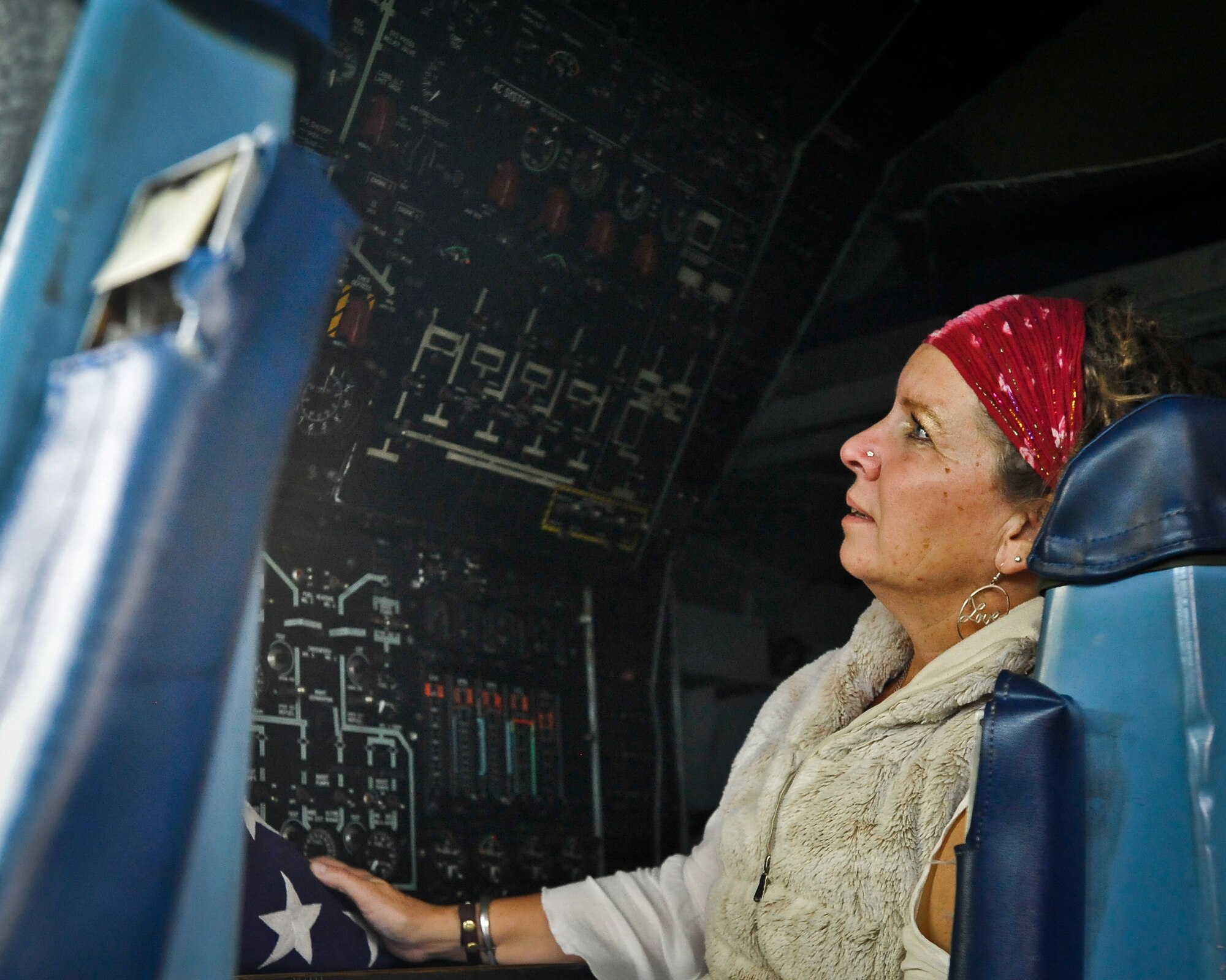 Alison Miller holds her husband’s flag in a flight engineer seat where her husband had worked on a C-141B Starlifter aircraft Sept. 29, 2014, at Joint Base McGuire-Dix-Lakehurst, N.J. Miller, widow of retired Air Force Master Sgt. Chuck Dearing, is traveling across the nation with her daughter Rachael-Grace Aganda to celebrate a late husband and father’s life on what they call an “Odyssey of Love.” (U.S. Air Force photo by Staff Sgt. Scott Saldukas/Released)
