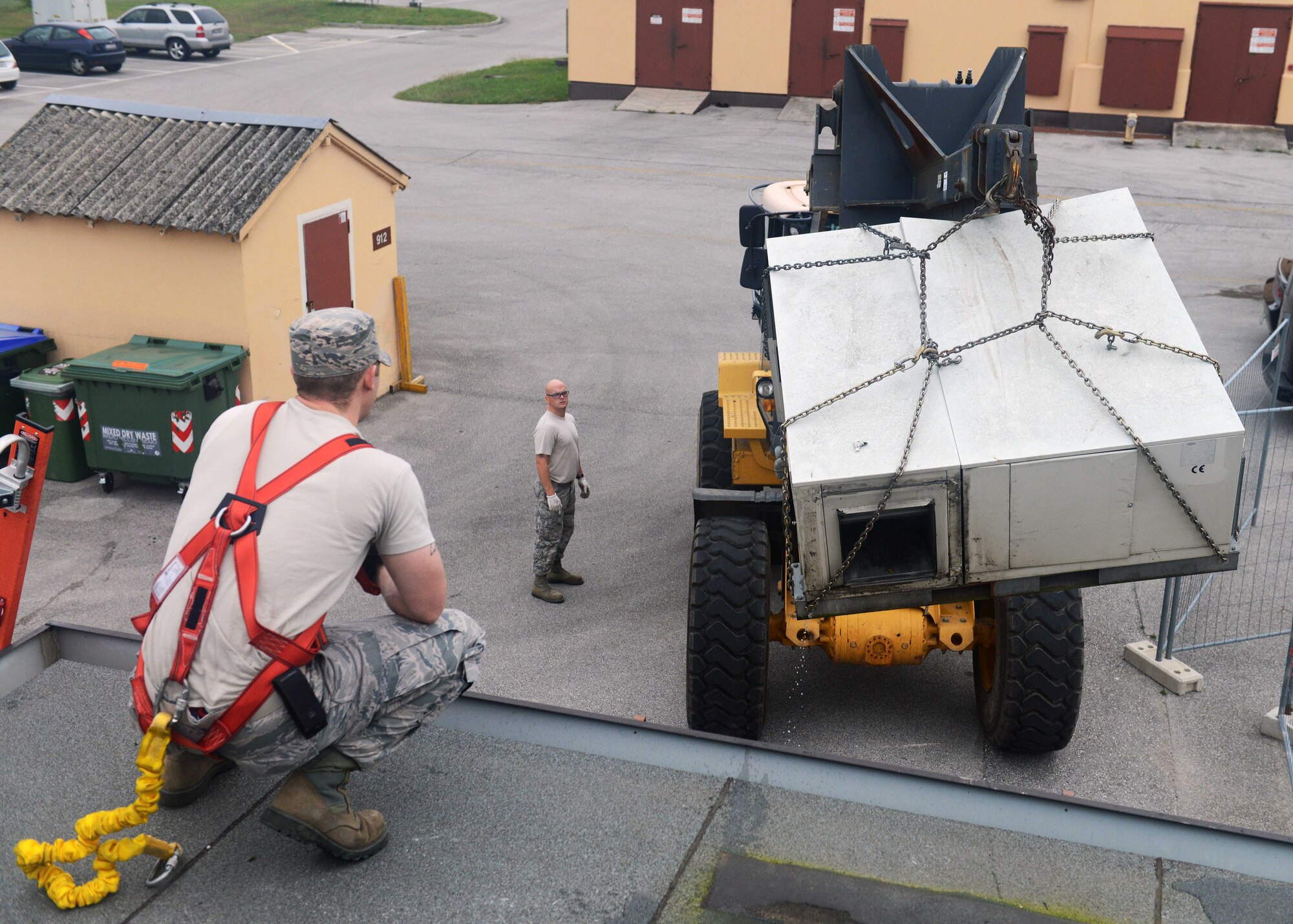 Senior Airman Matthew Sanders and Tech Sgt. Brandyn Walter observe as a heating unit is hoisted off a roof, Oct. 20, 2014, at Aviano Air Base, Italy. The 31 Civil Engineer Squadron Operations Flight are responsible for the water and fuel systems, structures, electrical units, heavy equipment, and heating and cooling systems on base. Sanders is a 31st CES heating, ventilation, air conditioning and refrigeration technician, and Walter is a 31st CES structures craftsman. (U.S. Air Force photo/Airman 1st Class Deana Heitzman) 