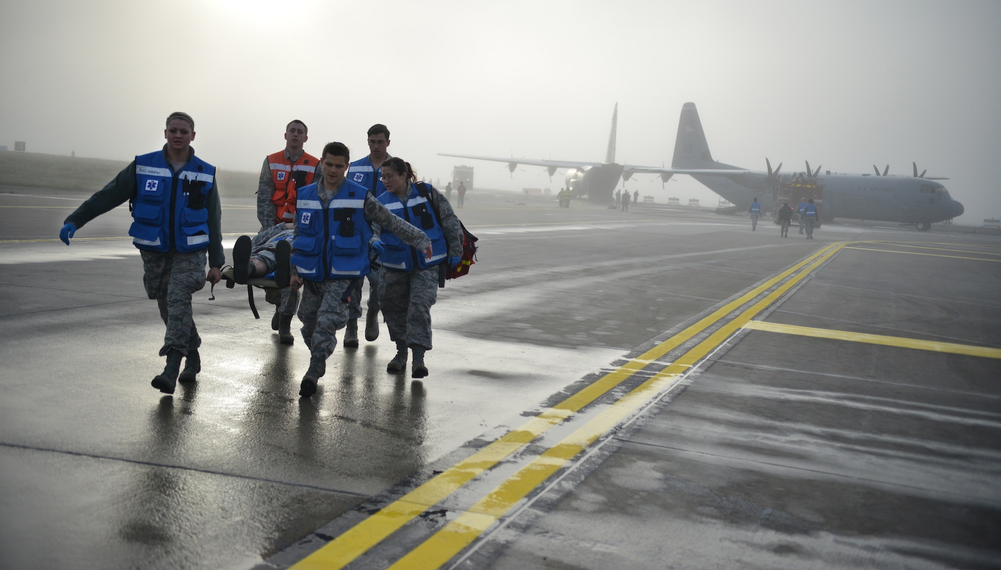 Medical personnel work together through the fog to assist in removing injured passengers of a simulated aircraft crash during the Major Accident Response Exercise on Ramstein Air Base, Germany, Oct. 18, 2014. Members of the U.S. Air Force and Host Nation agencies partnered in conducting a response and recovery exercise in preparation for possible real-world incidents. (U.S. Air Force photo/Senior Airman Hailey Haux)