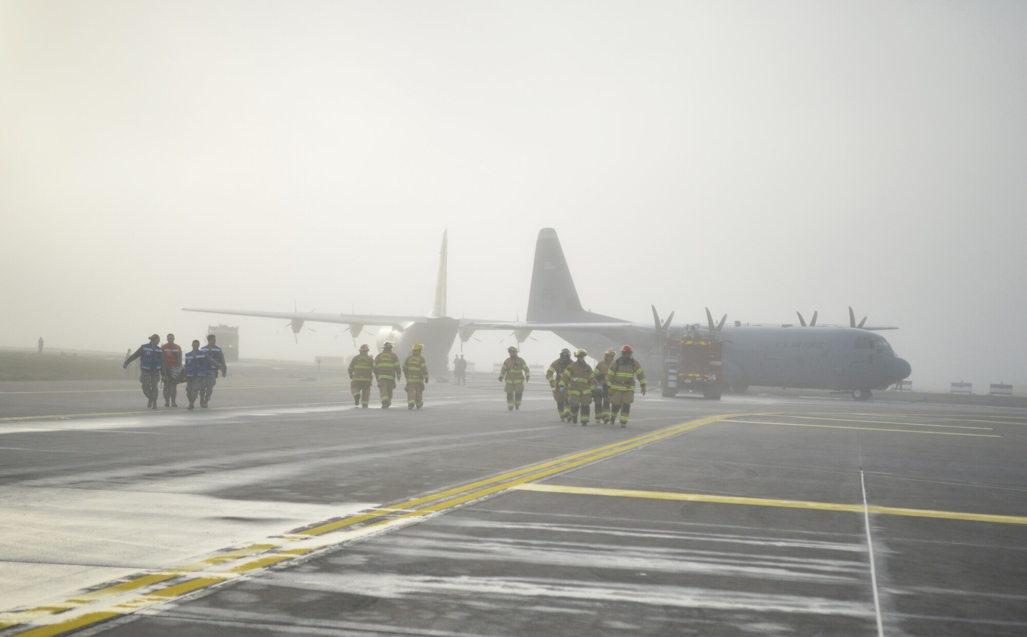 Firefighters and medical personnel work together through the fog to assist in removing injured passengers of a simulated aircraft crash during the Major Accident Response Exercise on Ramstein Air Base, Germany, Oct. 18, 2014. Members of the U.S. Air Force and Host Nation agencies partnered in conducting a response and recovery exercise in preparation for possible real-world incidents. (U.S. Air Force photo/Senior Airman Hailey Haux)