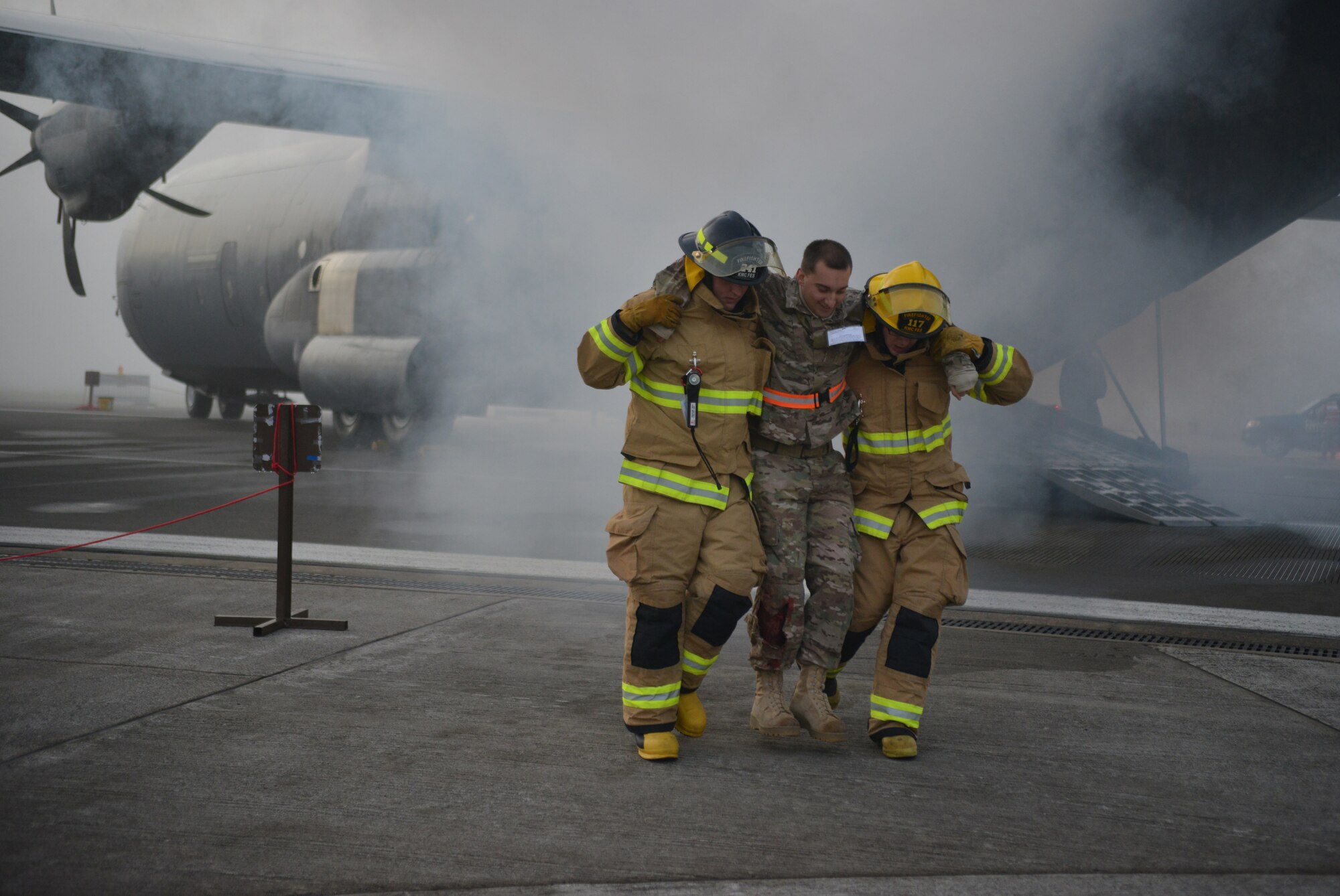 Firefighters remove an injured passenger from the wreck of a simulated aircraft crash under the watchful eyes of the Wing Inspection Team as part of the Major Accident Response Exercise on Ramstein Air Base, Germany, Oct. 18, 2014. Members of the U.S. Air Force and Host Nation agencies partnered in conducting a response and recovery exercise in preparation for possible real-world incidents. (U.S. Air Force photo/Senior Airman Hailey Haux)