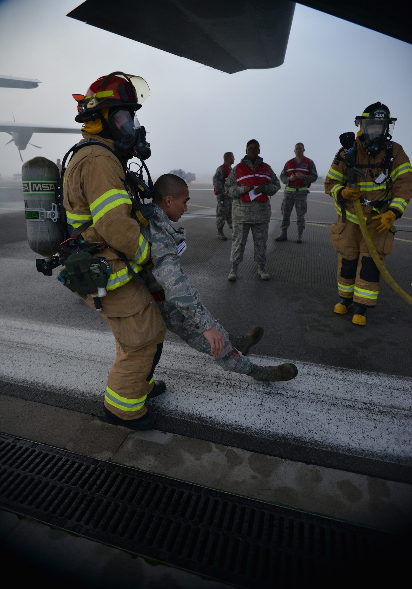 A firefighter removes an injured passenger from the wreck of a simulated aircraft crash under the watchful eyes of the Wing Inspection Team as part of the Major Accident Response Exercise on Ramstein Air Base, Germany, Oct. 18, 2014. Members of the U.S. Air Force and Host Nation agencies partnered in conducting a response and recovery exercise in preparation for possible real-world incidents. (U.S. Air Force photo/Senior Airman Hailey Haux)