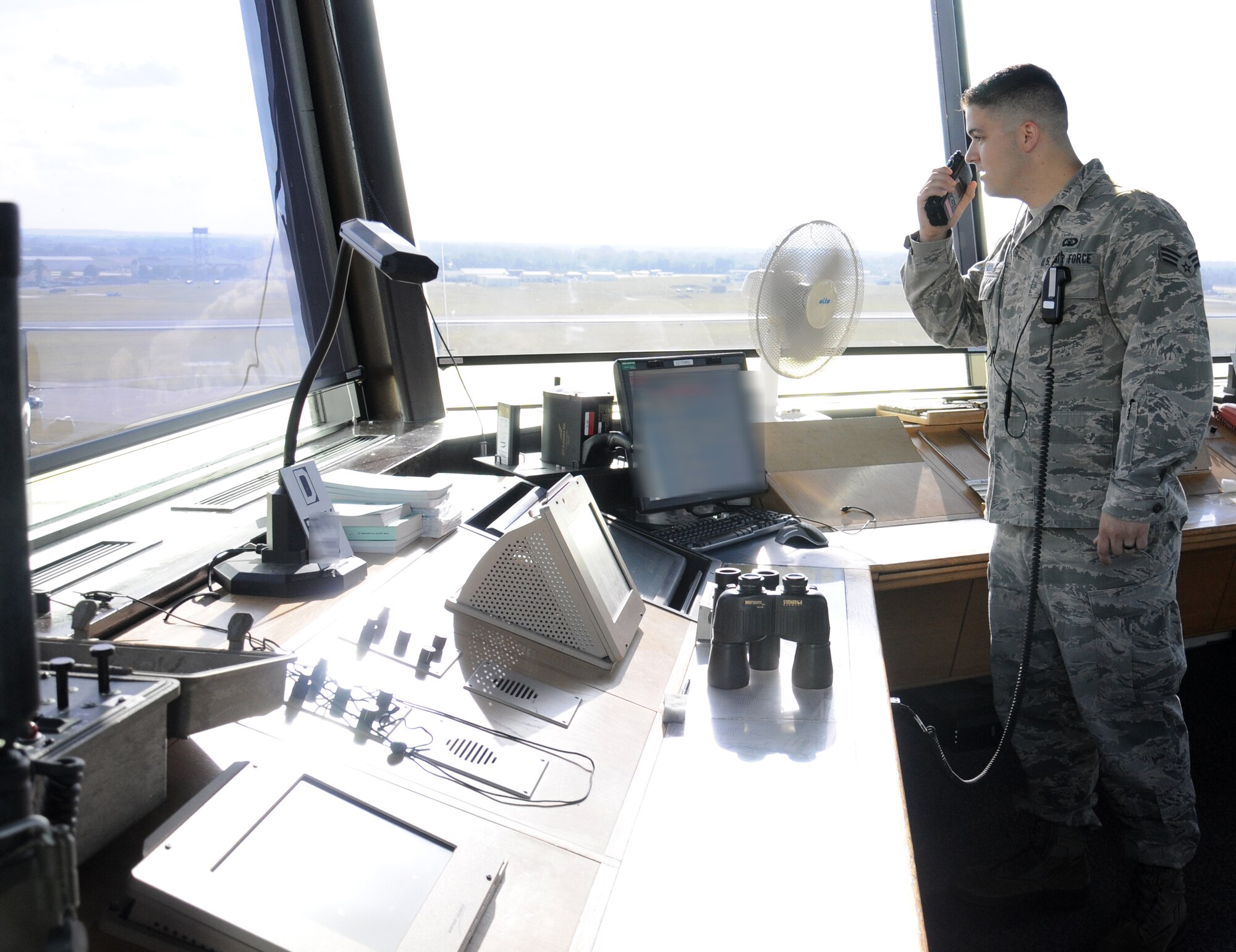 U.S. Air Force Senior Airman Andrew Kalina, 100th Operations Support Squadron Air Traffic Controller from Hoffman Estates, Ill., uses a hand held radio to communicate with ground personnel Oct. 3, 2014, on RAF Mildenhall, England. Kalina’s job involves ensuring aircraft and their crews are safe in the air, not only as they take off and land, but in the five miles of airspace surrounding base. (U.S. Air Force photo/Gina Randall/Released)