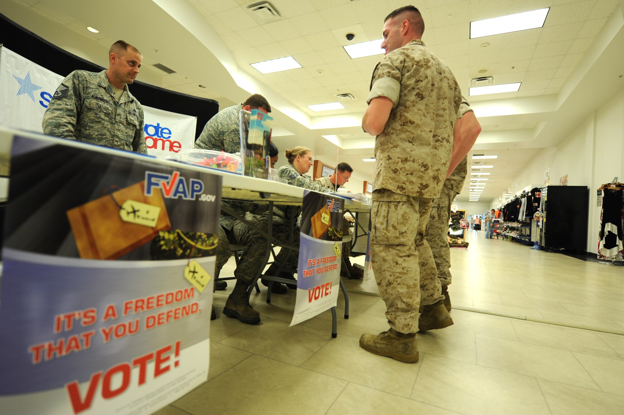 U.S. Air Force Capt Robert Espy, Kadena voting officer, and Marine Warrant Officer John Squares, Marine Core Base assistant voting officer, host a joint information booth on Oct. 21,2014, inside the Kadena Exchange, Okinawa, Japan. The event was hosted Oct. 20-22, from 11 a.m. to 1 p.m. and was hosted in an effort to push the importance of registering to vote, and assisting with absentee voting for those who want to vote absentee in the upcoming elections. (U.S. Air Force photo by Airman 1st Class Stephen G. Eigel/Released)