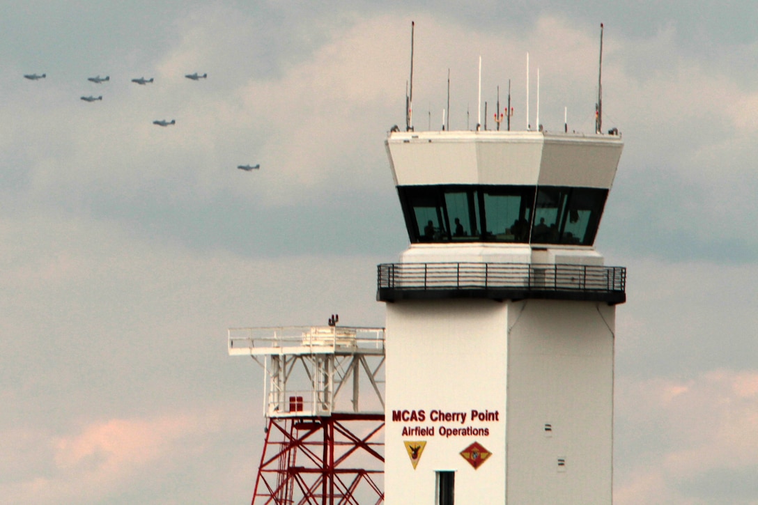 The air traffic control tower sits in the foreground as seven EA-6B Prowlers with Marine Tactical Electronic Warfare Training Squadron 1 take part in an historic seven aircraft flyover of Marine Corps Air Station Cherry Point, N.C., Oct. 16, 2014.
