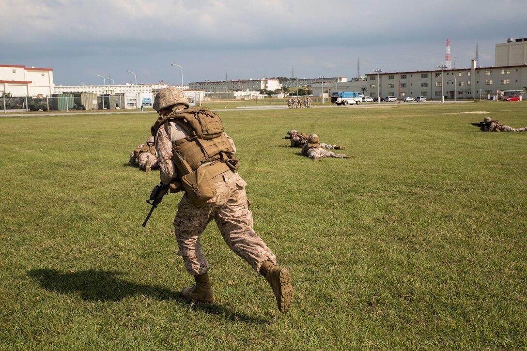 Marines execute squad rushes during the Air Naval Gunfire Liaison Company Basic Course Oct. 16 at Camp Hansen’s parade deck. The training day started with classes in the morning to refresh the Marines on the different tactics used during patrols. Following the class, the Marines practiced patrols and maneuvering under enemy fire. Using the techniques they learned in the class, the Marines were able to successfully engage simulated enemies from multiple directions during the patrol. The Marines are with 5th ANGLICO, III Marine Expeditionary Force Headquarters Group, III MEF. 