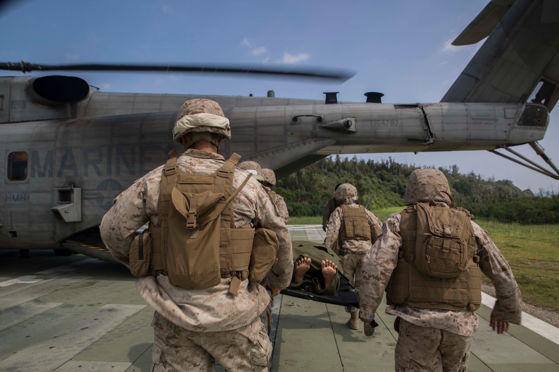 Corpsmen rush a casualty to a CH-53E Super Stallion helicopter during a medical evacuation drill Sept. 30 at the Kin Blue Training Area. The teams learned how to protect causalities on a stretcher while approaching a helicopter. The corpsmen are with 3rd Medical Battalion, 3rd Marine Logistics Group, III Marine Expeditionary Force. (U.S. Marine Corps photo by Lance Cpl. Rebecca Elmy/Released)